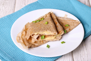Two pancakes filled cheese with green onion on a white plate