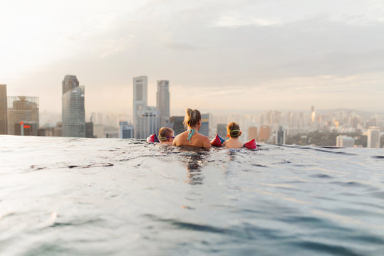 Mother and her children enjoying the view from roof top swimming pool in Singapore