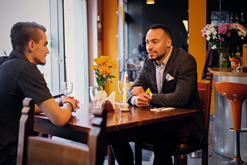 Two men talks and using a laptop in a restaurant.