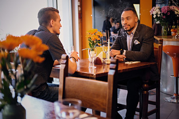 Two men talks and using a laptop in a restaurant.