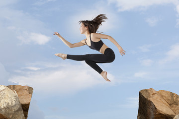 Woman jumping over the gap at blue sky