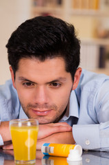 Handsome man watching the effervescent tablet in glass of water