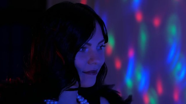 Sexy woman dressed in the style of a Great Gatsby flirting and dancing on party. Neon blue and red light.