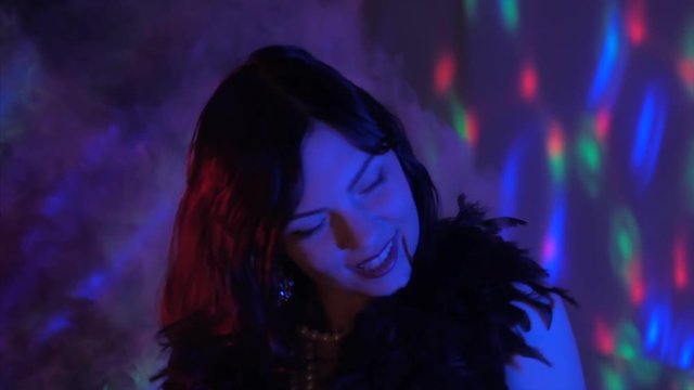 Sexy woman dressed in the style of a Great Gatsby flirting and dancing on party. Neon blue and red light.