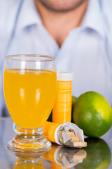 Lemon, pills of vitamin C and a glass of vitamin C dissolved over the table
