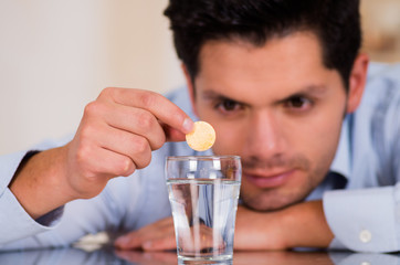 Handsome man dropping effervescent tablet in glass of water