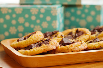Delicious freshly baked cookies with chocolate on a wooden tray with a blurred background