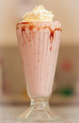 Delicious strawberry milkshake with syrup and cream on top