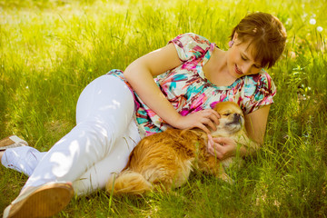 Mature american woman on weekend relax and have good mood, in grass on village with her friend a little dog