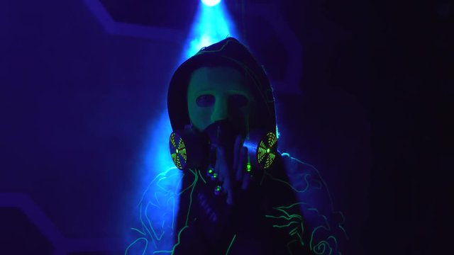 Cyborg man show with laser. Man in mirror costume in clouds of smoke in darkness