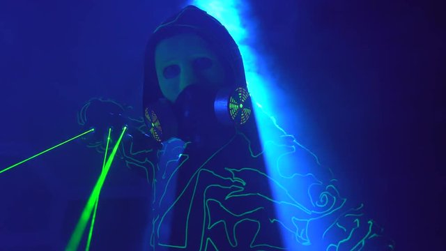 Cyborg man show with laser. Man in mirror costume in clouds of smoke in darkness