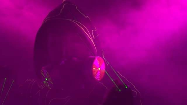 Laser man show. Man in mirror costume in clouds of smoke in darkness.