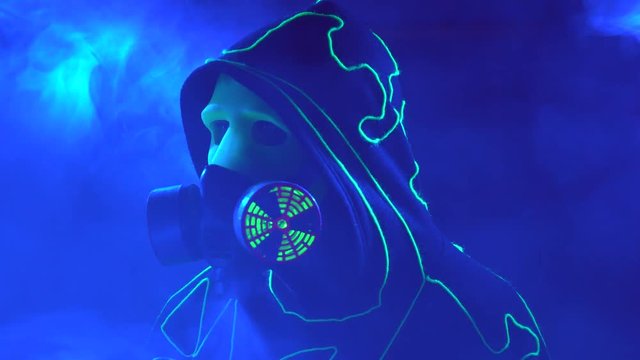 Laser man show. Man in mirror costume in clouds of smoke in darkness.