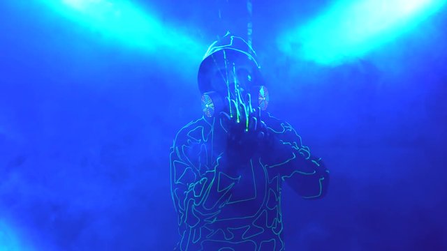 Laser man show. Man in mirror costume in clouds of smoke in darkness.