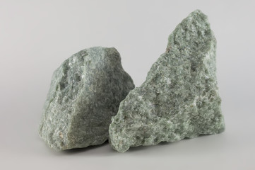 Close-up of two raw jade mineral stones, isolated on white background © Laricha
