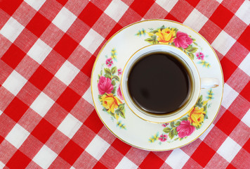 Cup of black tea in vintage cup on red and white checkered cloth with copy space
