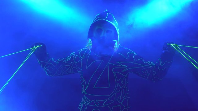 Laser man show. Man in mirror costume in clouds of smoke in darkness.