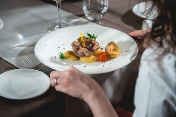 woman is preparing to eat delicious roulade of rabbit meat in a restaurant. small portion