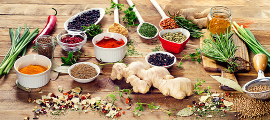 Colorful spices and fresh herbs on a wooden table.