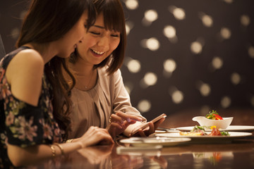 Fototapeta premium Women are watching smartphones while eating at the bar