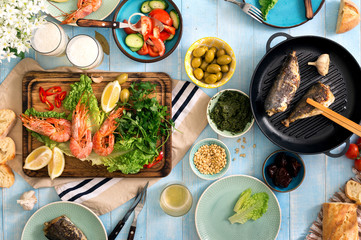 Dinner table with shrimp, fish grilled, salad, snacks and beer