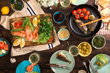 Dinner table with shrimp, fish grilled, salad, snacks and wine