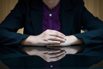 Businesswoman in suit sitting at a desk and clasp her hand