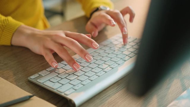 Woman hands typing on computer keyboard. Woman with yellow sleeves. Close up