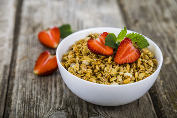 Granola with strawberry on a wooden table.