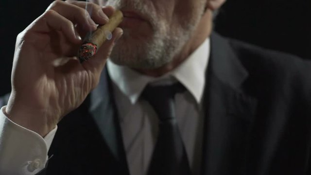 Arrogant gangster smoking expensive Cuban cigar, dangerous mafia, slow-motion