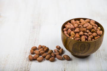 Peanut in a wooden bowl  on a  wooden table.
