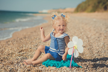 Cute girl on a sea side with two sea stars in blue dress.