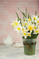 Spring breakfast. Cup of tea teapot, a bouquet of yellow flowers - daffodils and narcissus. Space for text. Vertical