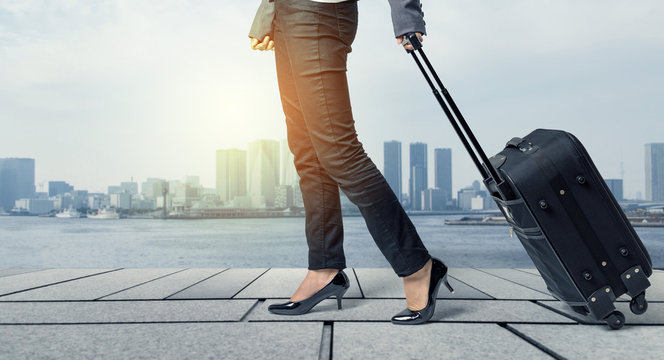 business woman walking by pulling a suitcase in downtown street.