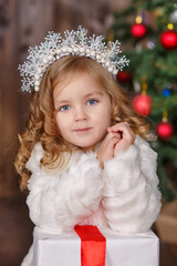 Fashion dressed girl lady with crown close to christmas tree with presents