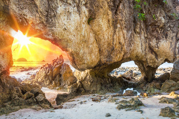 sunlight of passed tunnel rock on the beach at sunset