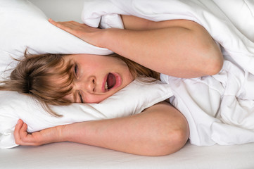Obraz na płótnie Canvas Woman with head under her pillow trying to sleep