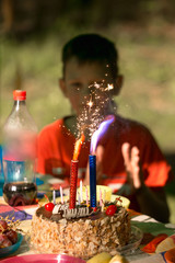 Celebration, holiday birthday cake with candles and fireworks light on a black background