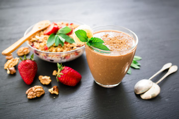 Oatmeal porridge with blueberries, strawberries and muesli on wooden background. Chocolate banana smoothie. Morning breakfast. Top view.