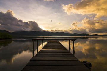 Scenic view of the wooden bridge to the sea. Against the backdrop of mountains and clouds.