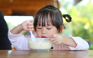 Little asian girl eating homemade ice-cream in cup.