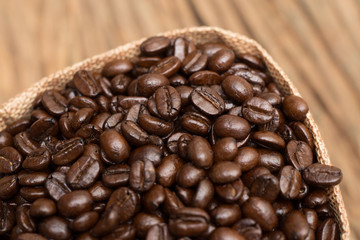 Sack of coffee beans on wood background