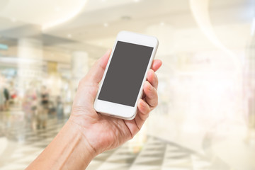 Hand holding mobile phone with abstract blur shopping mall background