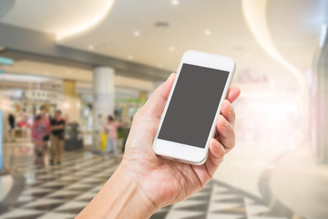 Hand holding mobile phone with blur shopping mall background