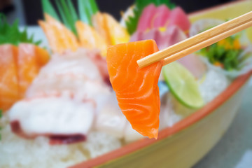 salmon in chopsticks with japanese sashimi set on boat plate