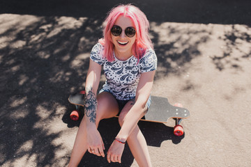 Top view of sporty beautiful smiling woman with pink hair wearing black sunglasses, with tattoo on...