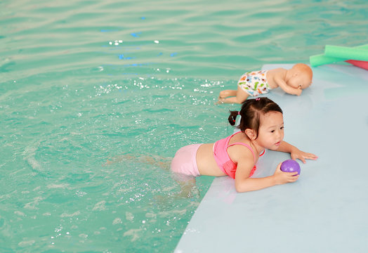 Little asian baby learning to swim.