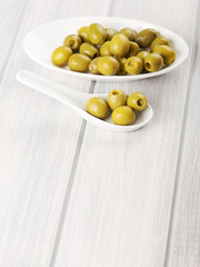 Stuffed olives on ceramic containers on white wooden table. Copy space. Vertical shoot.