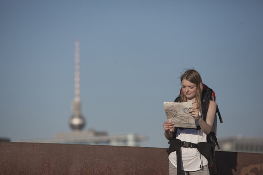 Germany, Berlin, Young woman with backpack looking at map