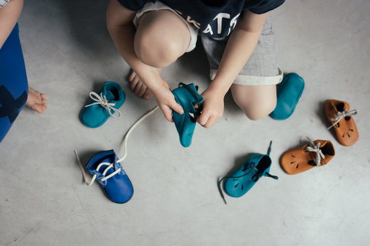 enfant qui joue avec des chaussons par terre